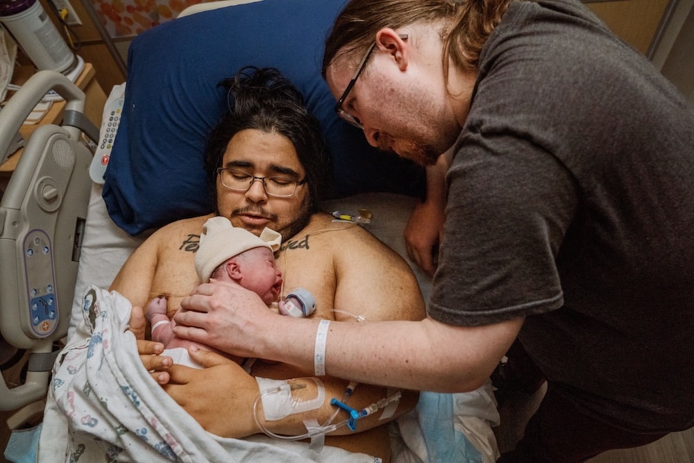New parents with baby on chest at a hospital birth.