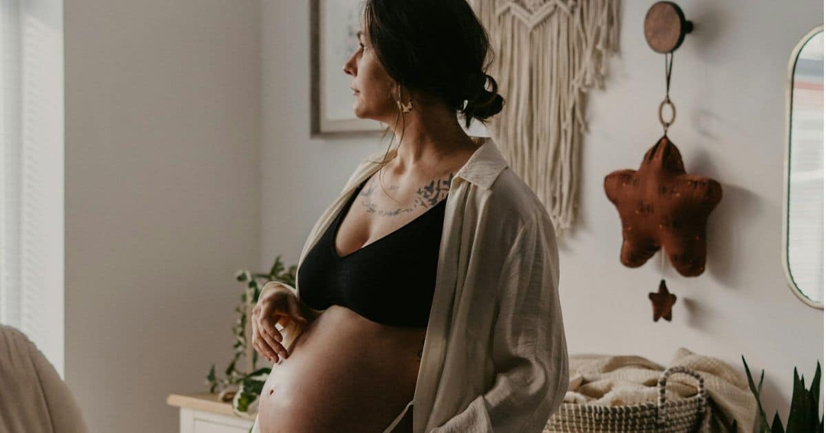 Pregnant person gazing out the window in baby's nursery