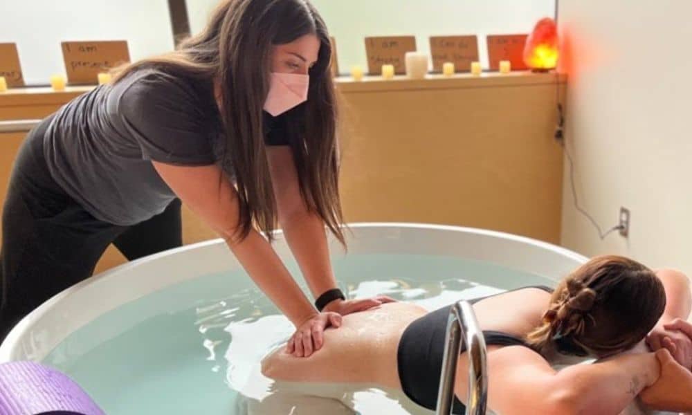 Salt Lake City birth doula supports pregnant parent laboring in birth tub with back pressure