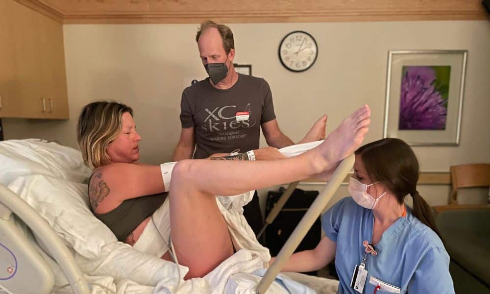 Birthing person using the squat bar to brace legs and push