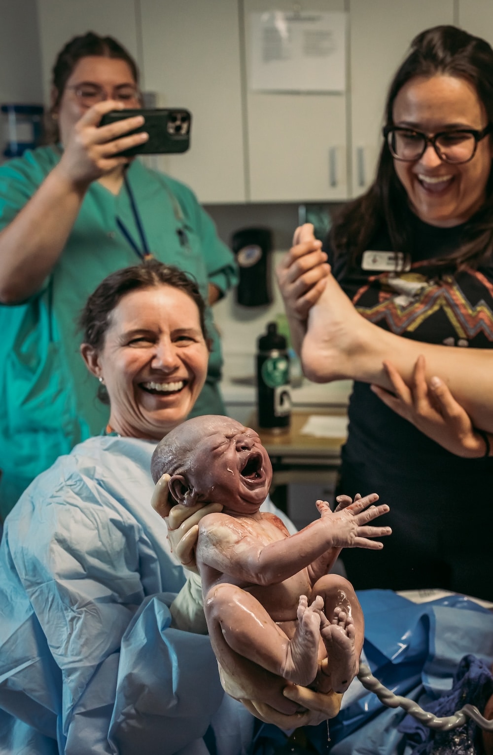 brand new baby with umbilical cord and support team smiling