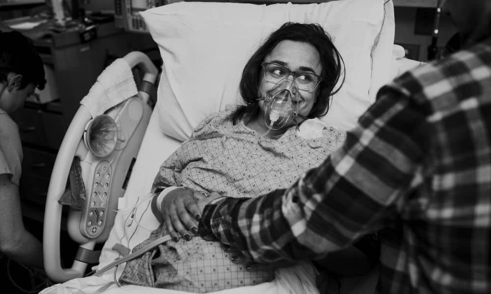 laboring in hospital bed with oxygen mask