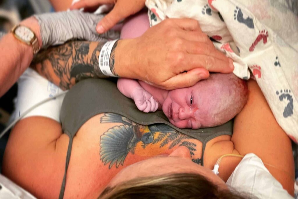 Newborn baby on mothers chest with tattos