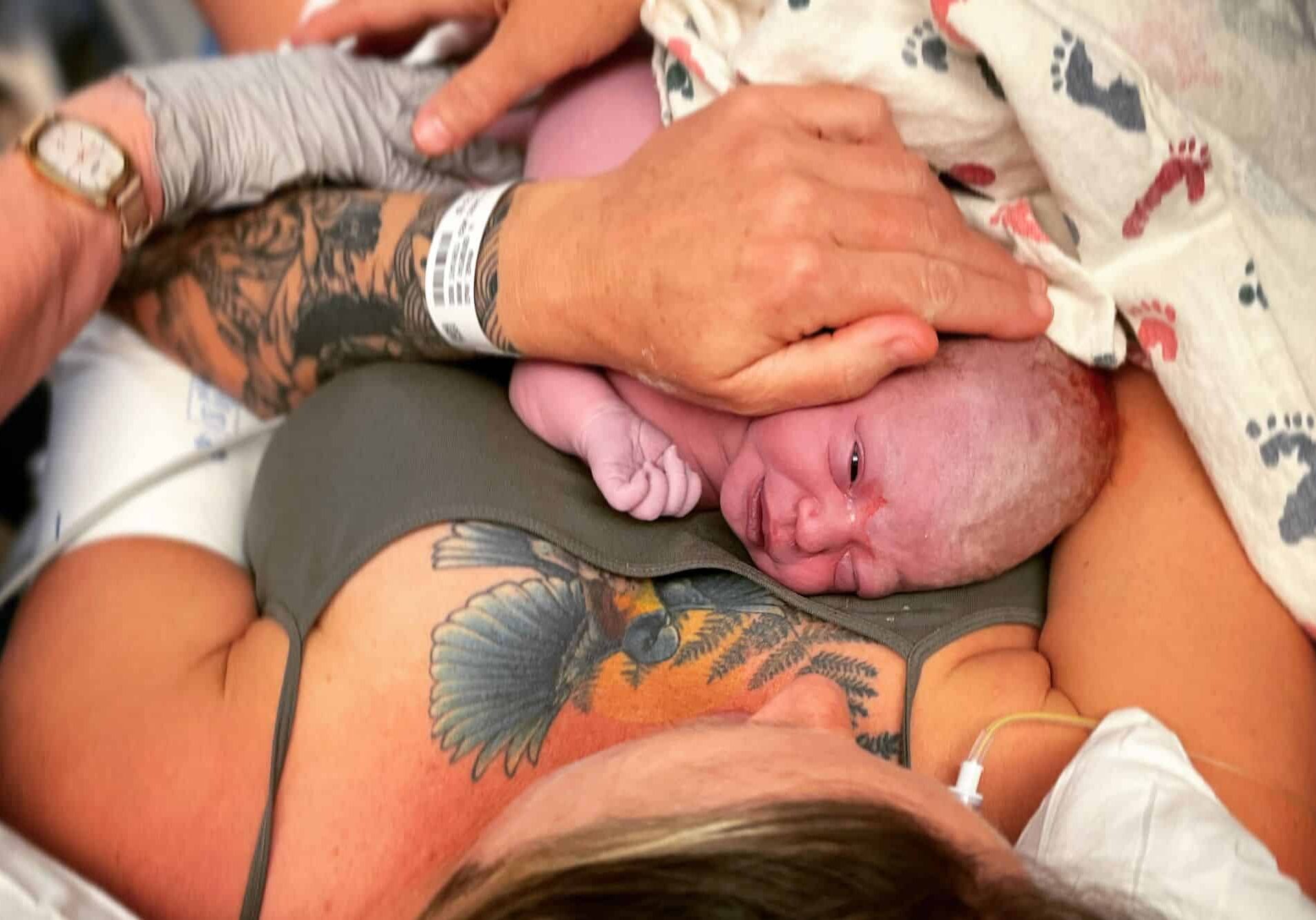 Newborn baby on mothers chest with tattos